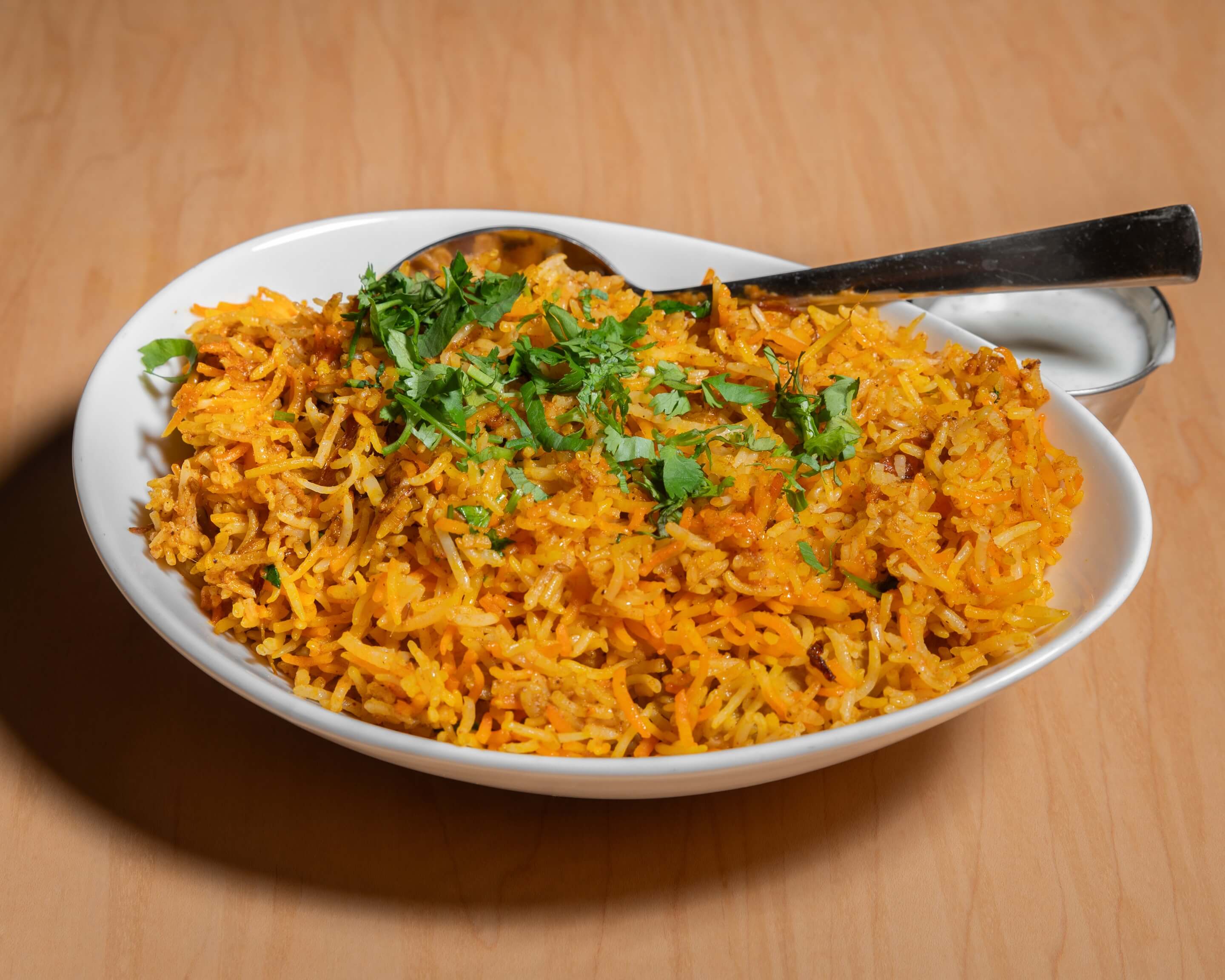 Biryani served with raita and salan on the side